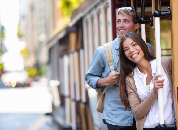 San Francisco city tourists riding cable car tramway tourism people lifestyle. Young interracial couple enjoying ride of cable car railway system, popular travel attraction.