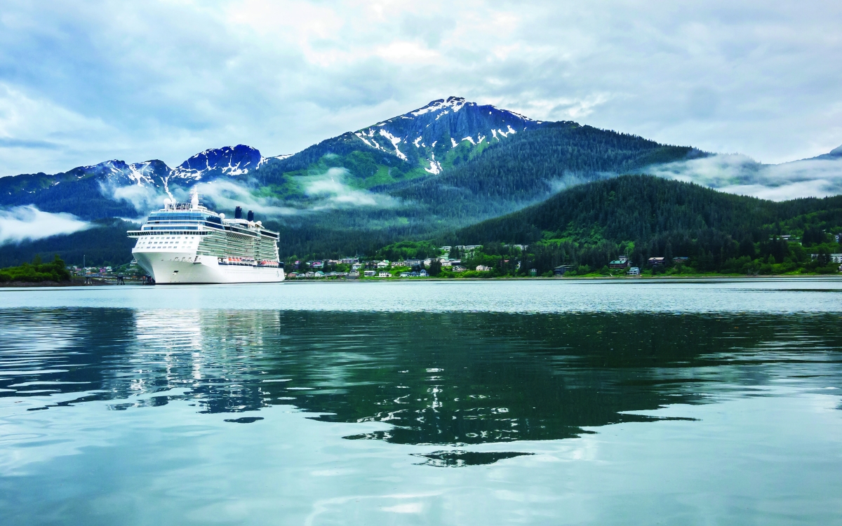 Cruise ship at a port in Juneau, Alaska with snow capped mountain and low lying fog in the background